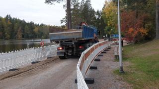 Kuorma-auto peruuttaa Kuusijärven rannassa työmaa-aidan vieressä.