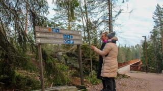 Kaksi henkilöä tarkastelemassa Kuusijärven ulkoilualueen opastetta