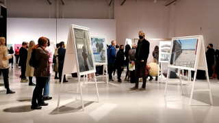 Ihmiset ihailevat valokuvia taidenäyttelyssä.