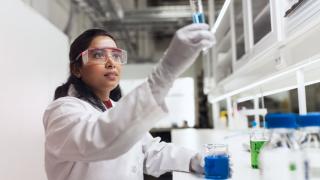 Henkilö ja laboratoriovälineitä.