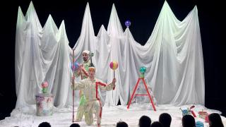 Kaksi sirkustaiteilijaa pyörittää palloja kepeillä. Lapsia lavan edessä. 