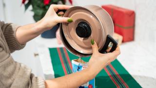 Nainen kaatamassa rasvajäämiä kattilasta tyhjään maitopurkkiin. 