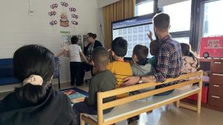 Päiväkodin lapsilla on meneillään aamupiiri. Opettaja näyttää taululta erilaisia säätiloja.