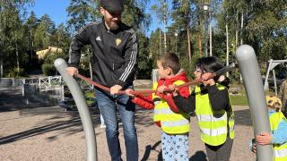 Varhaiskasvatuksen johtaja ja kolme lasta kiipeilevät kiipeilytelineessä.