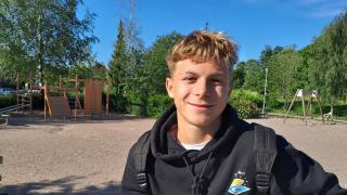 Dennis istuu penkillä koulun pihalla.