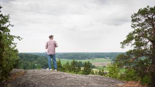 A man looks out over a wide open field.