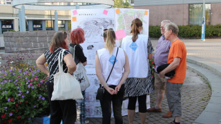 Ihmisiä ulkona tutkimassa karttaa.