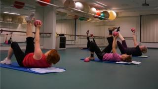 Ihmisiä jumppaamassa sisäliikuntatunnilla.