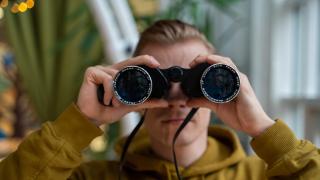 Mies katsoo kiikareilla.