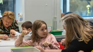 Lapsia pöydän ääressä juttelemassa ja askartelemassa.