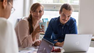 Kaksi henkilöä istuu kannettavan tietokoneen ääressä.