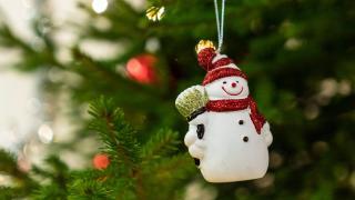 Joulukuuseen on ripustettu hymyilevä lumiukkokoriste.