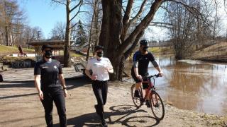 Kävelijä, juoksija ja pyöräilijä joen varrella.