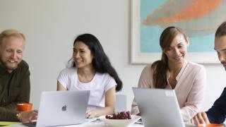 Hymyileviä ihmisiä kokouspöydän äärellä.