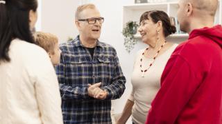 Eri ikäisiä ihmisiä keskustelemassa hyväntuulisesti.