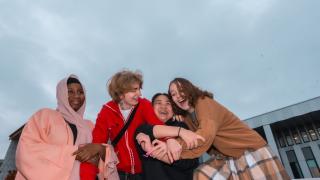 Neljä nuorta iloisen näköisinä, halaavat toisiaan.