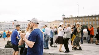 Ihmisiä tanssimassa parin kanssa Helsingin Kauppatorilla
