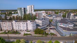 Myyrmäen keskustan kerrostaloja, liiketiloja ja junaraiteet ilmakuvassa.