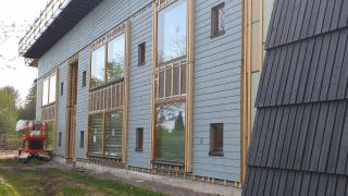 Rakenteilla oleva puinen päiväkoti, jossa on isot ikkunat.