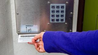 Käsi näyttää kirjastokortin lukijalle.