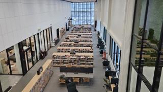 Yläviistosta otettu kuva kirjastosalista, jossa on paljon kirjahyllyjä.