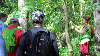 Ihmisiä luontoretkellä metsässä oppaan johdolla. 