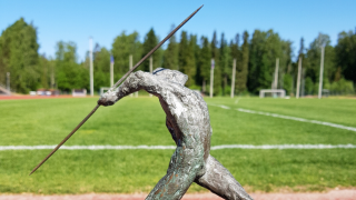 Keihästä heittävä patsas urheilukentällä.
