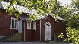 Kyrkoby skola är en traditionell röd skolbyggnad, omgiven av grönska.
