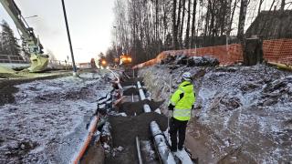 Turvavarusteisiin pukeutunut henkilö seisoo työmaalla selin. 