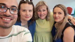 Kuvassa on neljä henkilöä, jotka katsovat hymyillen kameraan.