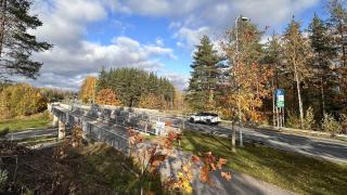 Auto kulkee sillan yli metsäisellä tiellä syksyllä ruskan aikaan. 