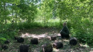 Marika Hyvärinen yhdeksän puupöllin ja maton kanssa metsän keskellä