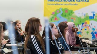 Kuvituskuva. Nuoret istuvat valtuustosalissa.