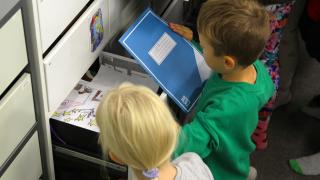  Barn letar efter anteckningsböcker från lådor.