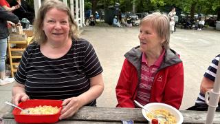 Kaverukset Marja ja Mirjam ovat syömässä puistoruokailussa. He istuvat pöydän ääressä ja heidän edessään on lautaset täynnä lohikeittoa.