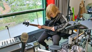 Lauri istuu tuolilla ja hänellä on basso sylissään.