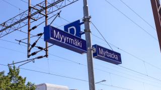 Myyrmäen aseman kyltti ja junien ajolankoja.