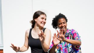 Kaksi nuorta tanssii iloisesti hymyillen.