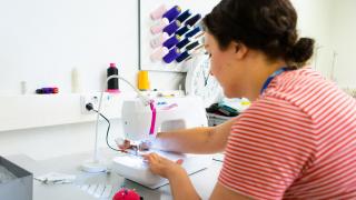 Nuori ompelee ompelukoneella.