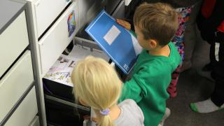 Oppilaat hakevat vihkoja laatikosta.