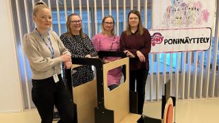 Patotien päiväkodin johtajat ja kaksi varhaiskasvatuksen opettajaa nojaavat leikkijunaan ja poseeraavat kameralle.