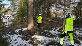 Työmaavarusteissa olevia ihmisiä kävelee metsässä talvella.