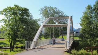 Pyöräilijä ylittää kävely- ja pyöräilysillan Tikkurilan jokirannassa.