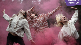 Tanssiesityksen tanssijat esiintyvät punaisessa savussa.