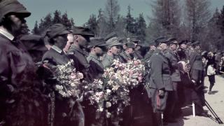 Ihmisiä seisomassa rivissä uniformuissaan, osalla kädessä kukkakimppu.