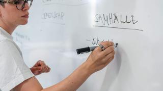 Opettaja kirjoittaa valkotaululle