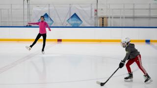 Luistelija tekemässä hyppyä ja lapsi pelaamassa jääkiekkoa jäähallissa.