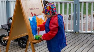 Lapsi maalaa ulkona terassilla.