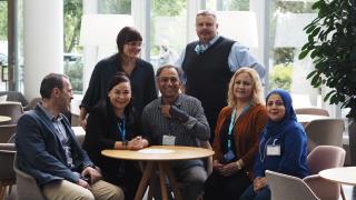 Kuvassa hankkeen tsempparitiimi istuu pöydän ääressä ja katsoo kameraan.