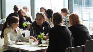 Ihmiset keskustelevat kaupungintalon kahviossa.